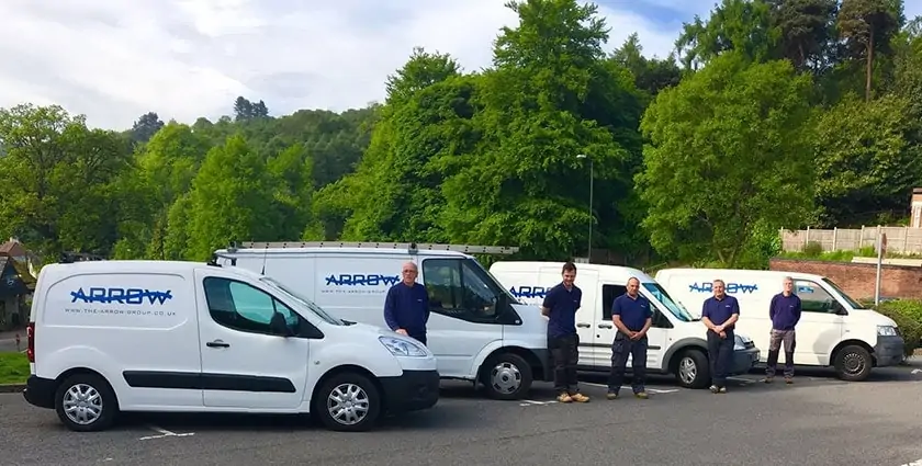 A team standing beside branded service vans parked outdoors.