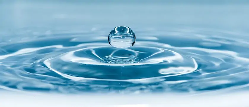 A water droplet creating ripples on a blue surface