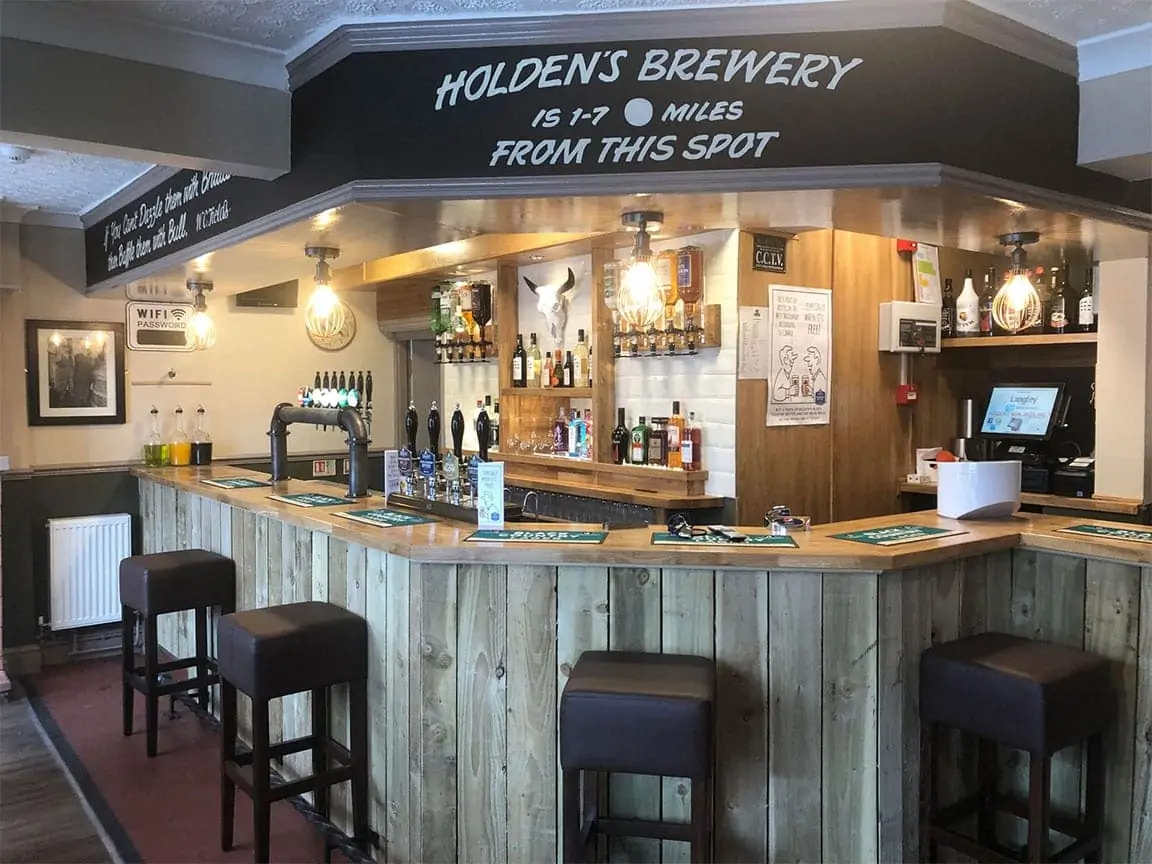 Refurbished pub bar with wooden counter, beer taps and bar stools