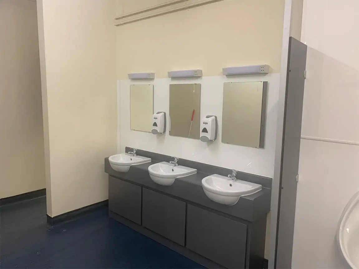 Three washbasins with mirrors and soap dispensers in a refurbished toilet block