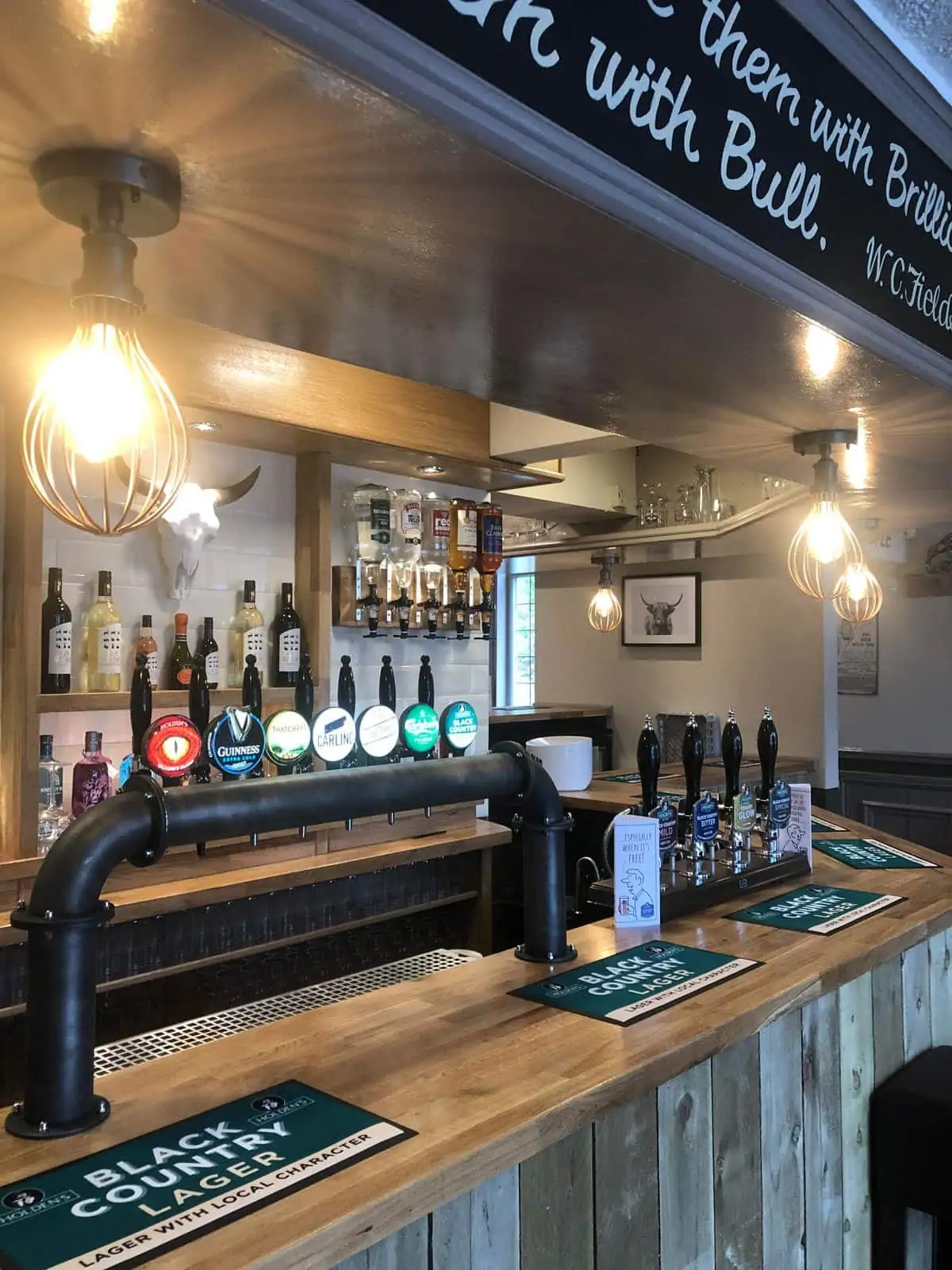 Wooden pub bar with a row of beer taps and warm pendant lights