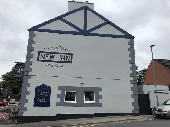 White pub exterior with dark blue decorative timber trim and New Inn signage.