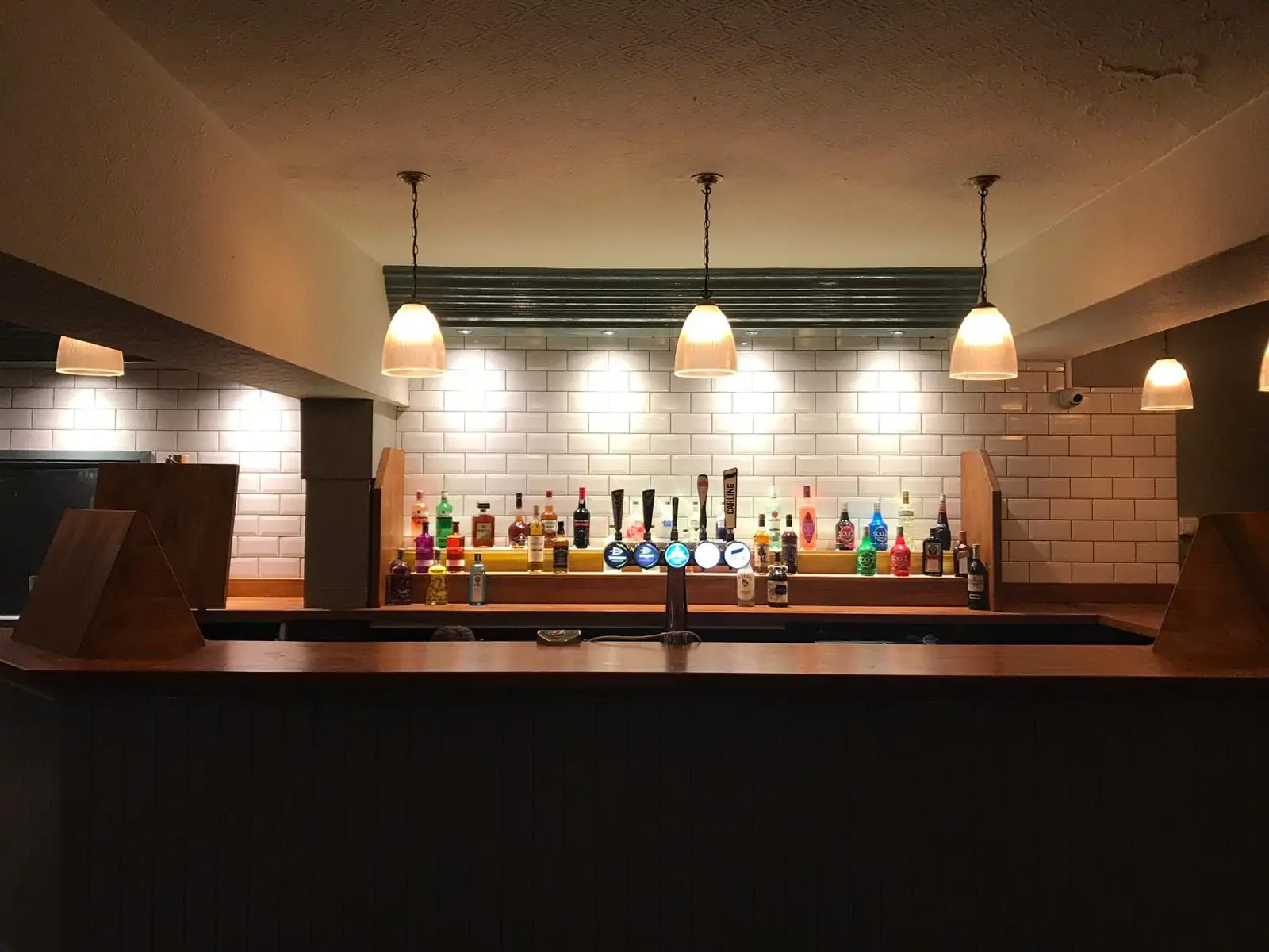 Refurbished bar with drinks taps, bottles and pendant lights