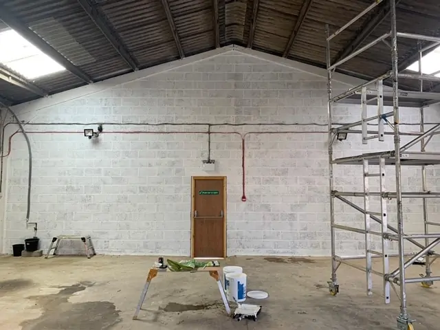 Empty commercial warehouse interior with scaffolding and decorating equipment