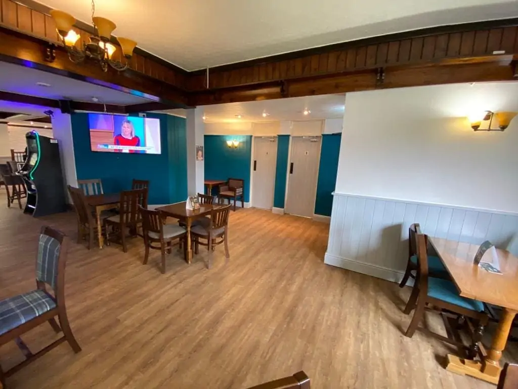 Dining room with wooden tables and chairs, teal walls and a television