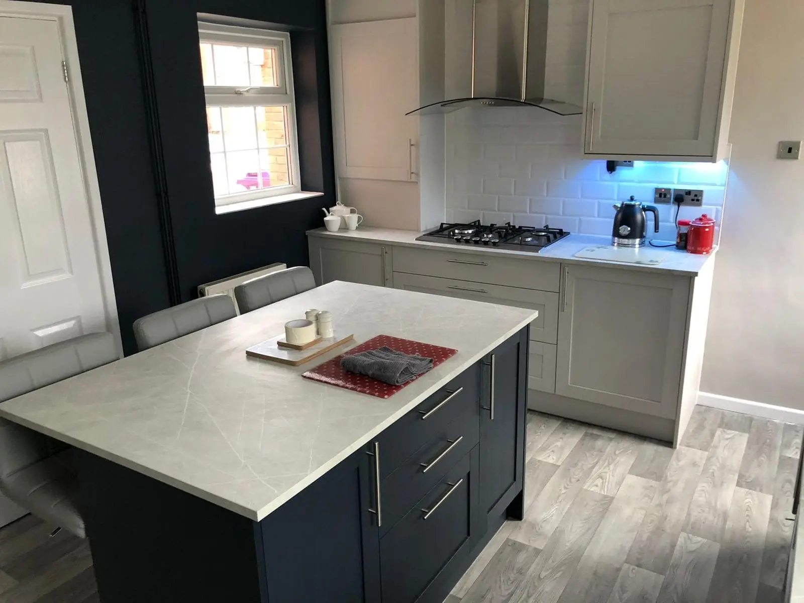 Modern kitchen with a dark island, pale worktops and shaker-style cabinets